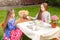 Girls having tea party with teddy bear at yard