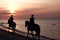 Girls horseriding on beach at sunset