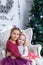 Girls hugging under Christmas magenta tree