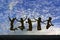 Girls jumping with Joy on the beach silhouetted against a cloudy sky