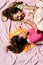 Girls lie on white and pink bed sheets background tickling