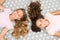 Girls with long curly hair lay on bed top view. Children perfect curly hairstyle looks cute. Conditioner mask organic