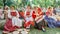 Girls in national Russian costumes are sitting on straw bundles