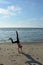 Girls performs handstand on sandy beach on the North Sea coast