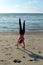 Girls performs handstand on sandy beach on the North Sea coast