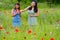Girls play ring flower in poppy field
