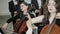 Girls play on violoncello in orchestra