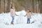 Girls play in winter forest and make snowman