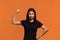 Girls power. Serious caucasian woman in black t-shirt raising hand while showing muscle, trying to look dangerous while. Ready to