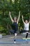 Girls practice yoga asanas in the outdoors park. Young women do exercises outside. Vertical frame