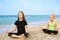 Girls practicing yoga on beach. Children are sitting in lotus position