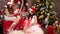 Girls prepare New Year`s cards and gifts to friends, Two friends pack festive boxes near Christmas tree, Funny winter