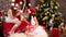 girls in Santa Claus hats near Christmas tree, Two friends wrapping festive boxes, On New Year`s Eve, sisters make
