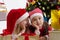Girls in Santa hats sharing secrets under Christmas tree