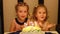 Girls sister on a child`s birthday. Children make a wish and blow out candles on the cake