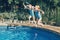 Girls sisters diving in water on home backyard pool. Children siblings friends enjoying and having fun in swimming pool together.