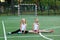 Girls sit on a twine on a sports field.