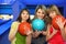 Girls stand alongside, hold balls for bowling