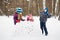 Girls stands behind wall made of snow blocks, boy throws snowball