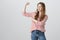 Girls are strong and powerful. Portrait of confident pretty caucasian girl raising arm with clenched fist, showing