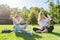 Girls students sitting on green lawn with digital tablet, drink bottle of water