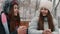 Girls teenagers talking, drinking warm drinks in a city park in snowy weather