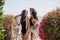 Girls in trendy swimwear posing next to beautiful blossoming bushes, while going to beach. Adorable young brunette