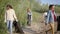 Girls volunteers clean the coastline from garbage. Women stack the garbage washed ashore in black bags. Ecological