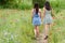 Girls walk back in poppy flower field