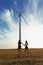 Girls walking next to a windmill. Electric windmill in the field on a sunny sky background. Youth concept. Copy space.
