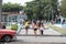Girls walking in a town square past a classic car in Havana, Cuba