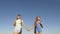 Girls, women travellers go holding hands on a background of blue sky. Close-up. Teamwork tourists teenagers. Women