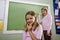 Girls writing on blackboard in classroom