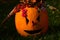 Girly carved gouged out pumpkin Hallowen Jack O Lantern lying with ponytails made of cornstalks and berries crown lying on lawn