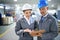 Give the order a once over. two managers standing inside a printing and packaging plant.