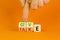 Give or take symbol. Concept word Give or Take on wooden cubes. Beautiful orange table orange background. Businessman hand.