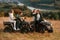 Giving high five and smiling. Two young couples with quad bikes is together on the field