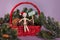 Giving time message held by wooden jointed manikin doll sitting in red basket full of pinecones and pine garland wearing Santa hat