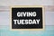 Giving Tuesday text on blackboard flat lay on wooden background