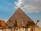 Giza, Egypt - January 29, 2020 - Tourist bustle with camels and people in front of a pyramid