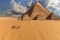 Giza Pyramids and camels in the desert under the clouds, Egypt