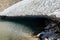 Glacial lake of melting ice of glacier and rocks in Summer. Partially frozen. Landscape scene in Aosta Valley in Italy. Climate