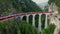 Glacier Express train on the famous viaduct in Switzerland - aerial view