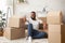 Glad african american guy sitting on floor with a lot of boxes