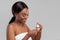 Glad attractive millennial african american woman applying cream or lotion on cotton pad