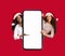 Glad black and arab young woman in Christmas hats show with hands on big phone with blank screen