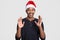 Glad black man raises hands and shows palms with happiness, wears Santa Claus hat, casual jumper, smiles broadly, shows perfect