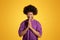 Glad black middle aged curly man in violet t-shirt prays with hands, isolated on orange background, studio