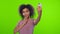 Glad black woman smiles broadly, takes selfie portrait on white cell phone