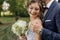 Glad, blissful, joyful smiling married couple of groom and bride in glasses with bouquet embracing in nature. Copy space